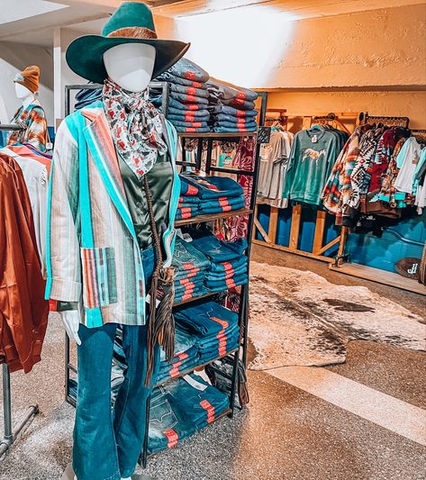 Business casual mannequin in a western serape blazer and Santa wild rag set up next to jean rack with kimes ranch jeans out front of a western boutique vendor booth display with hanging shirt racks in the back Tack Store Display Ideas, Western Boutique Display, Vendor Setup, Boutique Store Displays, Belt Store, Vendor Displays, Tack Store, Western Shop, Boutique Display