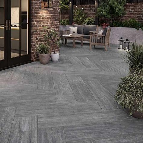 Experience the beauty of natural wood with our Forest Grey range, redefining your outdoor space in a resilient and captivating grey hue. These garden slabs, available in a textured plank format, offer versatility in styling, allowing for creative layouts in patios, raised areas, or as plank stepping stones amidst grass or gravel.  Unlike timber, our external porcelain tiles provide the beauty of wood without the need for sealing, ensuring durability and eliminating concerns of rot or slipperines Wood Effect Garden Tiles, Timber Look Tiles Outdoor Patio, Open Terrace Tiles Design, Veranda Tiles Floors, Tiles For Veranda, Tiled Outdoor Area, Outdoor Porcelain Tile Patio, Terrace Flooring Ideas, Porch Tiles Outdoor