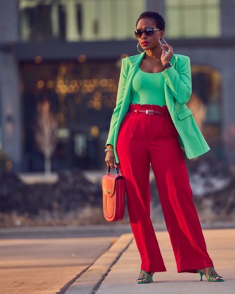 Style influencer Farotelle wearing a red and green color-blocked outfit. She has on high-waisted red pants with a fitted green top and a matching longline green blazer. She's wearing green strappy sandals and is holding a red handbag. She has short natural black and sunglasses. Green And Red Outfit, Red And Green Outfit, Pink Blazer Outfit, Colorful Wardrobe, Green Blazer, Stylish Work Attire, Wear Green, Pink Blazer, Red Pants