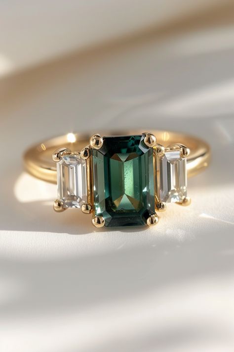 Discover the beauty of green emerald cut sapphire engagement rings and learn how to choose the perfect ring for your special someone. With its captivating color and unique cut, this gemstone will be cherished for a lifetime. Explore our top picks and expert advice on selecting the best quality ring for the most important question of your life. Green Proposal Ring, Emerald Green Engagement Rings, Green Sapphire Engagement Rings, Emerald Cut Gemstone Ring, Engagement Rings With Colored Stones, Emerald Green Ring Engagement, Non Traditional Wedding Rings Engagement, Emerald And Gold Engagement Ring, Emerald Wedding Ring Set