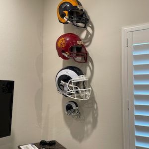 Helmet Display Ideas Man Cave, How To Display Football Helmets, Nfl Helmet Display Ideas, Football Helmet Display Ideas, Sports Memorabilia Display Wall, Helmet Display Ideas, Sports Memorabilia Display, Football Holder, Football Man Cave