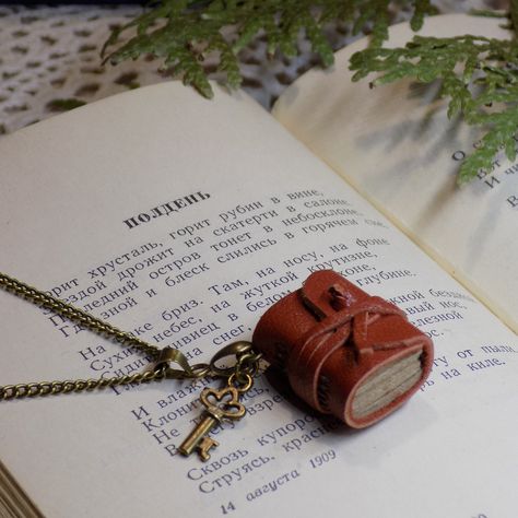 "This vintage-style hand-bound book necklace is made from citrine brown leather about 7/8\" tall (2 cm). The miniature usable journal pendant in cottagecore style can be a perfect Graduation or Christmas gift. If you are looking for a book club literary gift - this is it! This romantic tiny book charm with a bronze key in Jane Austen style is a perfect little bookish gift for journaling lovers, librarians, teachers, book nerds, and bookworms. ♡ Size: 3/4\"x7/8\"x3/8\"  (2x1.6x1 cm) ♡ Pages: 60 unruled sheets (120 pages) of 80 g/sq.m kraft  paper. ♡ Covers: citrine leather upcycled scrap ♡ Binding: Hand-bound Each little book is entirely handmade. This tiny book is hand-stitched and bound to a thin brown leather strap and has kraft light brown pages. A lovely small bronze key accents this j Bookish Jewelry, Journal Cottagecore, Book Charm, Cottagecore Jewelry, Book Pendant, Miniature Stuff, Long Stitch, Journal Jewelry, Leather Scrap