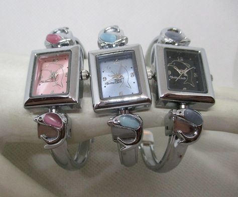 This is a new without tags Montres Carlo women's or teens quartz watch with a silver tone metal watch case, silver tone metal cuff watch band with glass cabochon dolphins. The pink and blue dolphins cabochon color matches the watch face color. They both have a silver tone dolphin 3 silver tone hands and silver tone numbers. The Gray dolphin watch has a black face with gold tone dolphin, gold tone numbers and silver tone hands. Japan movement, watch case and band made in China Watch length 7/8 in Unique Beauty Products, Handwritten Gifts, Grey Watch, Pink Dolphin, Pink Watch, Blue Face, Digital Closet, Cuff Watch, Blue Watches