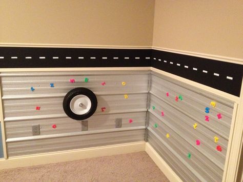 Metal activity wall for toddler boy room. My husband and Father in law used roofing tin for the walls. The tire (wheel barrel) spins on the wall. We outlined the tin with trim to eliminate sharp edges. Activity Wall, Toddler Boy Room, Oil Drip, Bedroom Stuff, Cars Room, Drip Pan, Toddler Boys Room, Toddler Activity, Boy’s Room