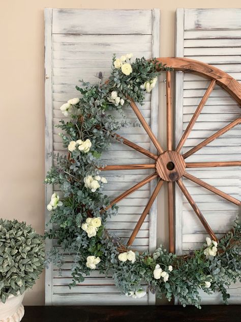 Floral Garland Wagon Wheel - The Hamby Home Wheel Decoration Ideas, Wagon Wheel Floral Arrangement, Wagon Wheel Decor Indoor Wall Ideas, Wagon Wheels Wedding Decor, Wooden Wagon Wheel Decor Outdoor, Wagon Wheel Decor Indoor, Wagon Wheel With Flowers, Wagon Wheel Wire Wreath, Wire Wagon Wheel Wreath