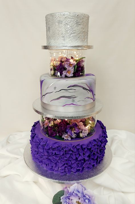 3-tier wedding cake with acrylic separator boxes filled with flowers and lights. This cake has a combination of tiers iced in buttercream and fondant. #weddingcakes #purple #silver #25thanniversary #adcbakery #jacksonvillenc Cakes With Acrylic Tier, Acrylic Tier Cake, Acrylic Cake Separator, Purple Tiered Cake, Cake With Acrylic Separator, Wedding Cake Silver, 3 Tier Birthday Cake, Sparkly Wedding Cakes, Cakes Without Fondant