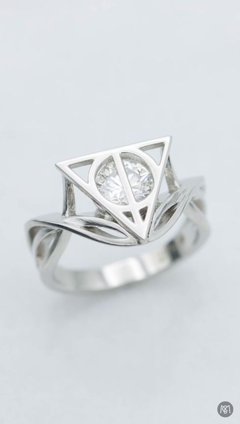 The delicate, vining platinum strands of this Harry Potter-inspired engagement ring balance the bold ring face, the symbol of the deathly hallows surrounding a bright, round brilliant diamond center stone. Harry Potter Engagement Ring, Harry Potter Wedding Rings, Nerdy Engagement Rings, Harry Potter Engagement, Harry Potter Ring, Stile Harry Potter, Harry Potter Wedding Theme, Buku Harry Potter, Harry Potter Jewelry