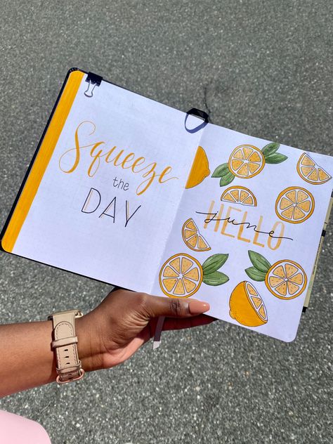 Black dotted notebook with white pages. Left side has a thick yellow stripe on the end with quote “Squeeze the Day” written in yellow and black with cursive and print fonts. Right side has whole and half lemons scattered across the page and “Hello June”. June written with black over Hello in cursive and Hello in yellow and large letters in caps. Photo is taken outside on blacktop Citrus Bullet Journal Theme, Lemon Bullet Journal, June Bullet Journal Cover Ideas, June Bujo, June Bullet Journal Cover, June Bullet Journal, Bullet Journal Month Cover, Bullet Journal Month, Bullet Journal Set Up