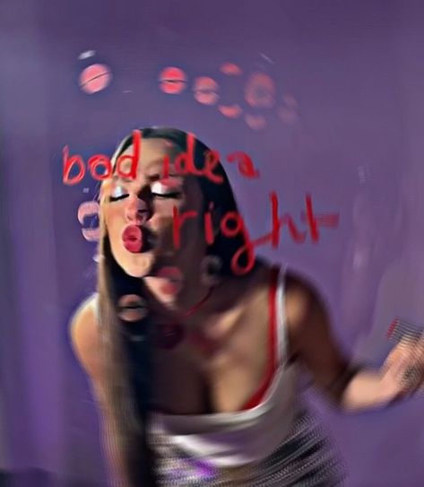 a picture of olivia rodrigo kissing a mirror that has the words “bad idea right” in red lipstick. olivia has on a white tank top and a black skirt with purple and gray. her hair is straight and she is wearing shimmery eyeshadow in a silver color and red lipstick. as she kisses the mirror, it leaves a read lipstick mark. her lips are puckered while kissing it. in her other hand she has the red lipstick. the walls of the room she is in are a dark purple that is associated with her “guts” album. Olivia Rodrigo Bad Idea Right, Olivia Aesthetic, Bad Idea, Only Girl, Save My Life, Olivia Rodrigo, Singers, Music, Quick Saves