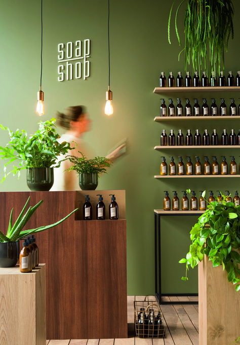 Green Retail Interior, Green Spa Interior Design, Green Retail Design, Shop Colour Ideas, Green Spa Room Ideas, Green Store Aesthetic, Accent Wall Retail Store, Earthy Retail Design, Green Store Design