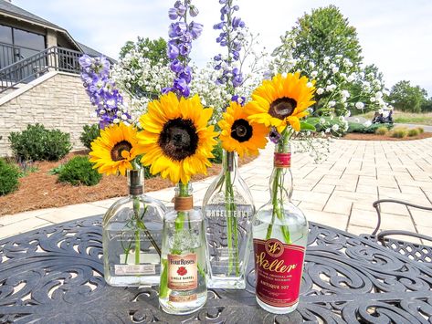 Bourbon Bottle Centerpieces for a "Whiskey & Wildflowers" event theme. Sunflowers, baby's breath, and purple delphiniums. #centerpieces #bourbon #wildflowers #whiskey #eventdesign Empty Liquor Bottles, Bourbon Bottle, Bottle Centerpieces, Dream Dream, Whisky Bottle, Wedding Bottles, Event Themes, Center Pieces, Liquor Bottles