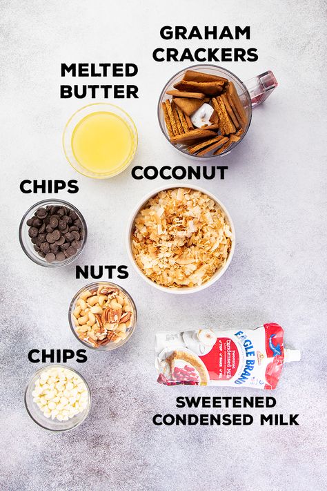 Ingredients for 7 layer bars in bowls with pouch of Eagle brand sweetened condensed milk 7 Layer Bars Eagle Brand, Layer Bars Recipe, 7 Layer Bars, Gluten Free Graham Crackers, Layer Bars, Coconut Chips, 7 Layer, Eagle Brand, Chocolate Nuts