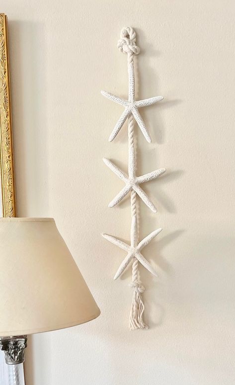 "Starfish Door/Wall Hanger Bring a beach feel to your home with this natural Starfish Rope Hanger...a novel alternative to a traditional wreath.  Included are three natural Starfish on a twisted ivory cording.  Easy to hang from the top loop.  Add a big red or green bow and it's ready for the holidays! Each starfish measures  5\"-6\" and the overall length is approximately 24\".  See the rest of The Seashell Collection here - http://www.seashellcollection.etsy.com" Coastal Door, Seashell Collection, Beach Themed Crafts, Diy Beach Decor, Starfish Decor, Traditional Wreath, Nautical Crafts, Rope Decor, Shell Crafts Diy