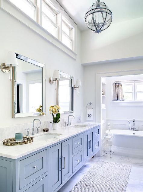 Located under a high ceiling, clerestory windows are positioned over beveled vanity mirrors lit by nickel and glass sconces. White And Tan Bathroom, Tan Bathroom, Room Floor Tiles, Ceiling Bathroom, Cheap Bathroom Remodel, Cabinets Design, Large Bathroom, Cheap Bathrooms, Diy Ceiling