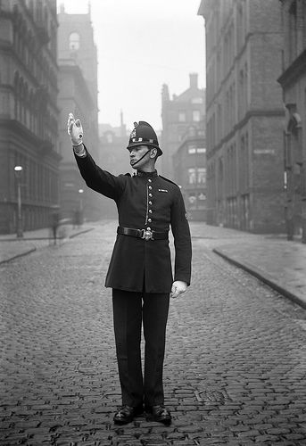 A wonderfully preserved image of a Manchester City Police officer on point duty in central in the city around 1914.    Before the electronic traffic light became widespread, officers would control junctions during busy periods. This practice was known as point duty and each officer would be allocated a ‘point’ and set times at which he was to attend. http://www.gmpmuseum.com 1930s Police Uniform, 1930s British Fashion, Victorian Police Uniform, 1920s Police Officer, British Police Uniform, British Police Officer, Victorian Policeman, Constable Police, The 39 Steps