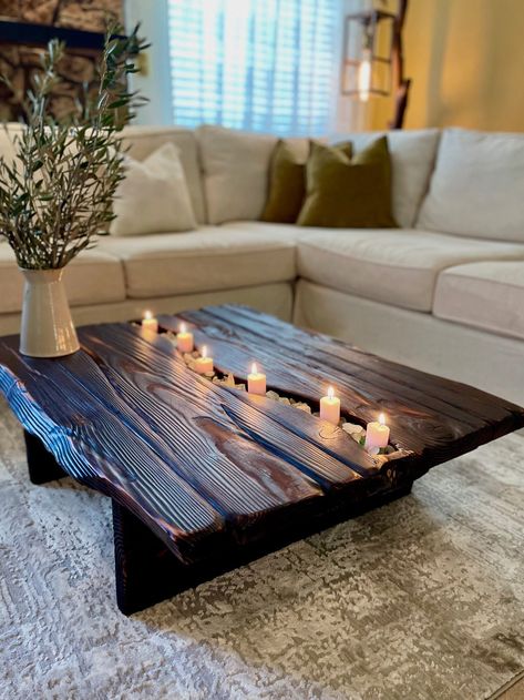 38"L x 30"W x 12"H (Ask for a custom size) Our Venezia Coffee Table is a charismatic rustic centerpiece that features faux live edges to imitate a beautiful slab design from douglas fir lumbers. Its deep black carbon finish, induced through the ancient Japanese wood-burning technique Shou Sugi Ban, pairs nicely with its elegant slender frame. Furthermore, the rectangular top has a carved river in the middle which you can garnish and style freely. *Candles and pebbles not included* Giant Coffee Table, Rustic Home Furniture, Rustic Coffee Table Ideas, Coffee Table Alternative Ideas, Dark Rustic Living Room, Coffee Table Ideas Diy, Dark Coffee Table, Faux Live Edge, Coffee Tables Ideas