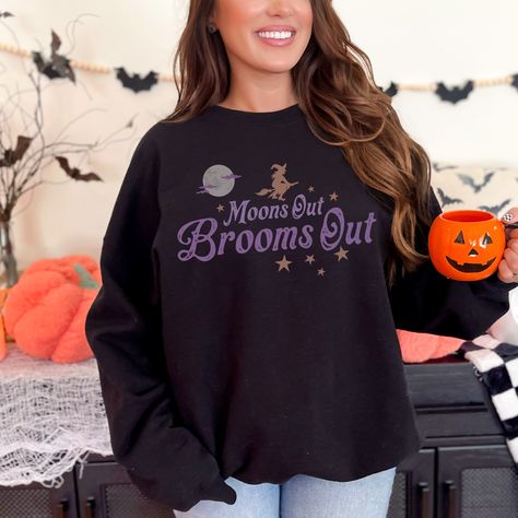 🌕 "Moons Out Brooms Out" Halloween Crewneck Sweatshirt 🧙‍♀️Get ready to cast a spell of style this Halloween with our "Moons Out Brooms Out" Crewneck Sweatshirt. Whether you're brewing up some mischief, attending a coven gathering, or just enjoying a moonlit night, this enchanting sweatshirt is your ticket to a magical Halloween.🌙 Witchy Moonlit Scene:This bewitching crewneck features a captivating scene of a witch soaring past a full moon on her broomstick. The detail in this graphic is so spellbinding; you can almost feel the cool night air and hear the rustling of leaves.👕 Premium Comfort:We've printed this enchanting design on a Gildan® 18000 Unisex Crewneck Sweatshirt, renowned for its plush softness, warmth, and long-lasting quality. It's like wrapping yourself in a cozy spell.🎨 Halloween Crewneck Sweatshirt, Witchy Shirt, Witch Sweatshirt, Halloween Crewneck, Cast A Spell, Moonlit Night, Flying Witch, To Cast, Brooms