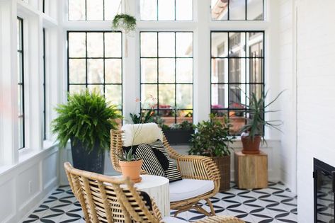 Sunroom windows accented with black panels complement black and white geometric floor tiles positioned beneath a white and gold stool accent table flanked by wicker chairs topped with black and white pillows. Black And White Sunroom, Door Transom, Sunroom Design Ideas, White Sunroom, Small Conservatory, Jean Stoffer Design, Sunroom Windows, Jean Stoffer, Small Sunroom