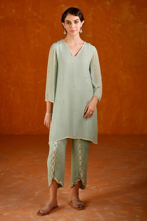 Teal bead and pearl embroidered tunic crafted in georgette base. Paired with a matching georgette dhoti style tulip pant with cutdana embroidery and scallop details. Components: 2 Pattern: Embroidered Type Of Work: Pearl, Bead Neckline: V Neck Sleeve Type: Three-quarter Fabric: Georgette Color: Blue,Green Other Details:  Length: Tunic length: 35 inches Tulip pant length: 36 inches Note: Bag shown in the image is not for sale. Occasion: Mehendi and Haldi - Aza Fashions Dhoti Style Pants, Bottom Designs Pants For Kurtis, Tulip Pants With Kurti, Pant Designs For Kurti, Pant Style Suits Indian, Pant Plazo Design, Pants Design For Kurti, Summer By Priyanka Gupta, Plazo Designs