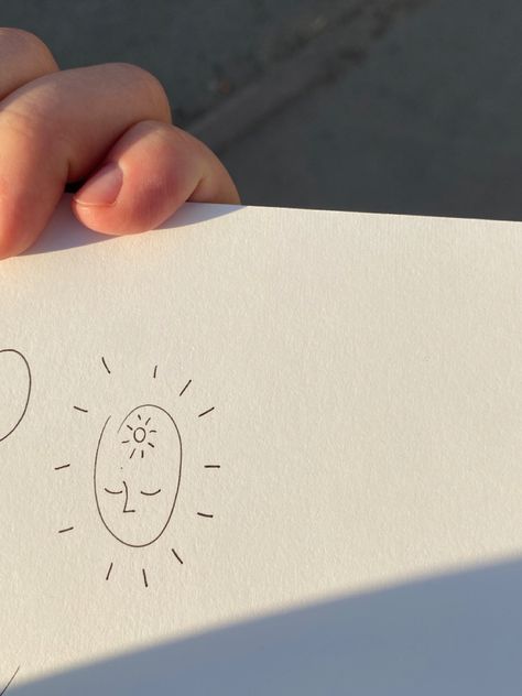 photo of minimalist little sketch on the sketshbook on the street at the sun. flash is about small dumpy face with cute sun inside the head and sunshine lights from the face I’ll Give You The Sun Tattoo, Sun Doodle Tattoo, Sun Smile Tattoo, Sun Light Tattoo, Love And Light Tattoo, Hand Holding Sun Tattoo, Little Sun Tattoo, Sunlight Tattoo, Light Tattoo Ideas