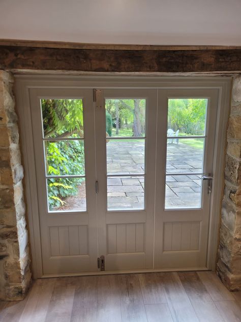 White bi-fold doors in a conservatory. The door is closed with a view out onto a large garden. Bifold Doors With Windows, Green Bifold Doors, Bifold Doors Kitchen, Bifold Doors Extension, Bifold Garage Doors, Oak Bifold Doors, White Bifold Doors, Internal Bifold Doors, Bifold French Doors