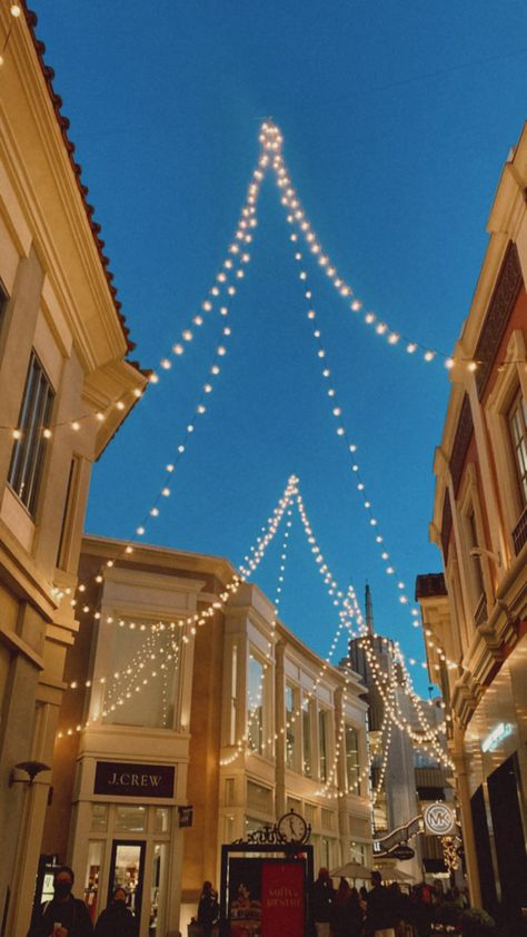 String lights hanging from the tops of the stores at the grove in Los Angeles as the sun sets and darkens The Grove Aesthetic, West Hollywood Aesthetic, The Grove Los Angeles, Los Angeles Mall, Los Angeles Nightlife, Los Angeles At Night, Aura Photo, Coca Cola Wallpaper, Los Angeles Aesthetic