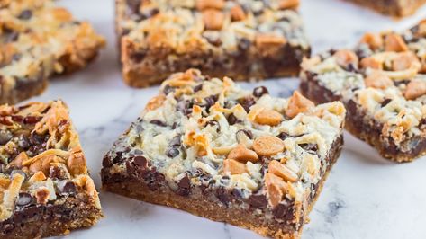 If you're craving an ooey, gooey cookie bar that's reminiscent of your childhood, this 7-layer cookie bar recipe totally delivers. It's also super easy to make! 7 Layer Cookies, Dolly Bars, Christmas Party Snacks, Magic Cookie Bars, Gooey Cookies, Caramel Bits, Chocolate Graham Crackers, Cookie Bar, 7 Layer