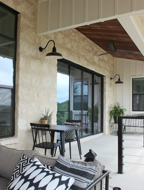 Rustic farmhouse back porch on a home in the Texas Hill Country. Limestone, white board and batten, a rusted tin ceiling, and black accents really make the home a unique beauty!  #customhome #farmhouse #texashillcountry #newconstruction Austin Stone Exterior Texas Hill Country, Texas Hill Country Limestone Homes, Limestone Farmhouse Exterior, Austin White Stone Exterior, Austin Limestone Exterior, Limestone And Black House Exterior, Limestone And Board And Batten Exterior, Rock And Board And Batten Exterior, Texas Limestone House Exterior