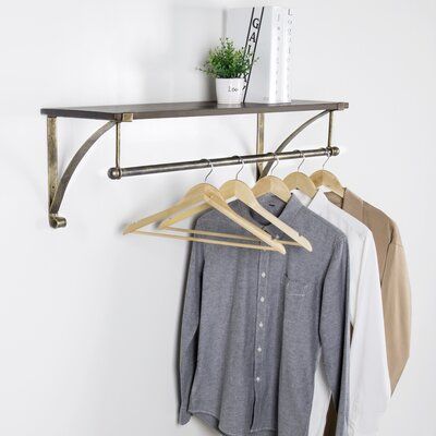 Stylishly display clothing in a home or retail environment with this 35-inch wall-mounted coat and hat rack. Featuring a 35 x 12-inch shelf and 35-inch clothes hanger rod, this garment display shelf offers a perfect blend of space and style for merchandising clothing in a shop or providing decorative storage for coats, hats, and purses in the home entryway. Its rustic finish and bronze-tone metal construction are great for adding a decorative accent to any living space and can be easily installe Wall Mounted Clothing Rack, Metal Floating Shelves, Hanging Bar, Wood Floating Shelves, Estantes Flotantes, Clothes Drying Racks, Hanging Clothes, Garment Racks, Clothes Rack