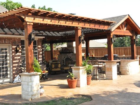 A patio cover and arbor are the perfect combination for an outdoor living space.  Here we have a beautiful Austin Stone Fireplace, with a divine outdoor kitchen and island combination.   The perfect backdrop for your gatherings! Call us at 214-603-8071 to schedule your free onsite consultation. Pergola Extension From Covered Patio, Pergola Patio Extension, Covered Stone Patio, Outdoor Kitchen Ideas Under Pergola, Pergola With Fireplace Attached To House, Large Pergola Covered Patios, Adding Pergola To Existing Covered Patio, Backyard Pergola Attached To House, Pergola Connecting House And Garage