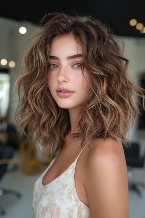 Person with wavy brown hair and a neutral expression in a brightly lit room. Medium Brown Hair With Balayage Caramel, Wavy Brown Hair With Blonde Highlights, Face Light Hair, Sun Kissed Balayage Brunettes, Brunette Balayage Hair Curly, Golden Brunette Hair Balayage, Brunette Honey Balayage, Curly Balayage Hair Brunettes, Warm Honey Brown Hair Balayage