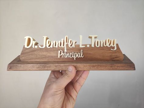 This specially designed table sign is made entirely of natural wood. The table name holder will attract attention with its elegant design. The Personalized Nameplate leaves its peers behind with its natural and decorative appearance. Custom nameplate with your name and title gives your desk a distinctive look. Our products are made of natural wood. In this product, the name parts are made of poplar wood and the pedestal on which the names sit is made of walnut wood. The ground is made of pine Table Name Holders, Natural Wood Desk, Custom Desk Name Plates, Name Holder, Custom Name Sign, Desk Name Plate, Custom Desk, Teacher Desk, Desk Name