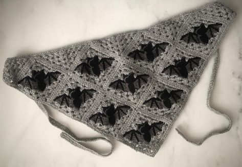 Step into the mysterious realm of gothic elegance with our Triangle Crochet Bat Head Scarf. This black and grey crochet head scarf features a captivating bat design, perfect for adding a touch of spooky charm to your Halloween ensemble. Crafted in a generous 19x13x13" triangle shape. Each tie strap measures 13.5" long, allowing for versatile styling options to suit your unique look. Elevate your outfit with this enchanting accessory, ideal for those who appreciate gothic aesthetics and love to stand out with distinctive pieces. Embrace the dark allure of this head scarf and let your inner mystique shine through all season long. Bat Shawl Crochet, Black Crochet Ideas, Simple Crochet Gifts, Bat Shawl, Head Scarf Crochet, Crochet Gothic, Crochet Head Scarf, Crochet Handkerchief, Bat Head