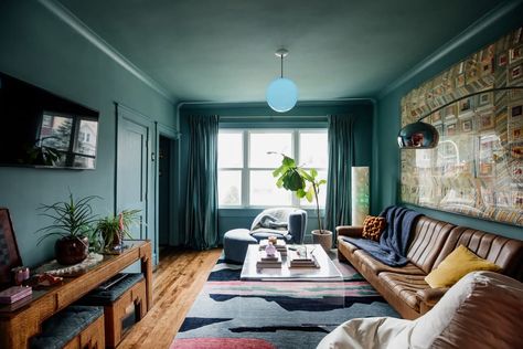 Blue pendant turned on in blue hued living room with large quilt hung above brown leather sofa in light filled room. Eclectic Vintage Bedroom, Mid Century Modern Leather Sofa, Floor Ottoman, Couch Accessories, Chicago House, Modern Leather Sofa, Hay Design, Design Page, Modern Color Palette