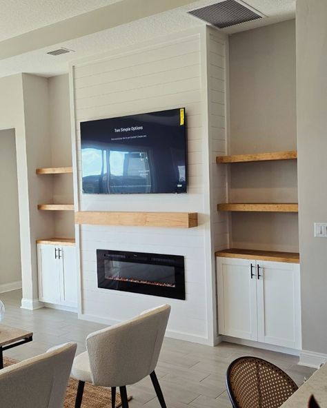 Elevate your living space with our custom entertainment center designs! 🎨✨ This latest project showcases a beautiful blend of modern aesthetics and functional design, featuring built-in shelving, a sleek electric fireplace, and a perfectly mounted TV. The natural wood accents add warmth and contrast beautifully against the shiplap backdrop, creating a cozy and inviting focal point in this home. Whether you’re looking to upgrade your living room or create a stunning feature wall, we’ve got yo... Modern Living Room With Electric Fireplace, Fireplace Shelving Ideas Built Ins, Custom Entertainment Center Built Ins, Diy Built In Entertainment Center, Shiplap Backdrop, Built In Wall Units, Custom Entertainment Center, Natural Wood Accents, Wall Entertainment Center