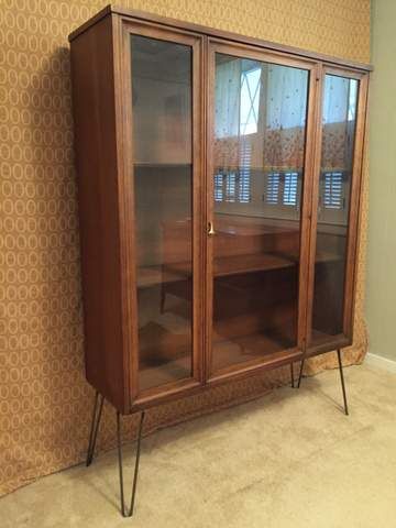 Sitting on bare hairpin legs with a glass front and two fixed interior shelves, this mid century modern walnut display cabinet from the Brasilia line features signature hardware and … Mid Century Modern Glass Cabinet, Modern Glass Cabinet, Broyhill Brasilia, Interior Shelves, Loft Studio, Hairpin Legs, Idea Board, Glass Cabinet, Signature Hardware