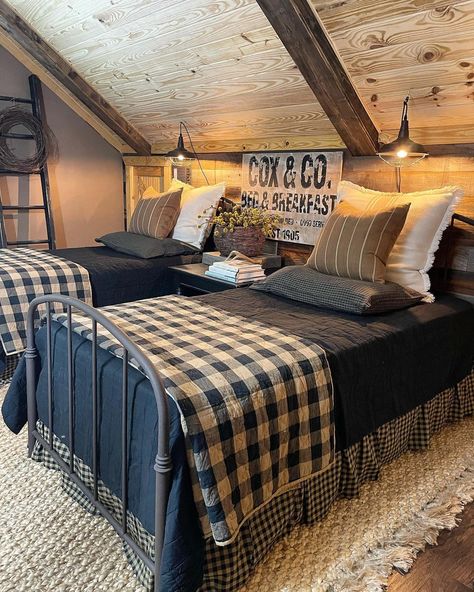 Two blue metal twin beds are pushed against a wood shiplap bedroom wall. Blue, beige, and white pillows are strewn at the head of the bed. Blue bedspreads cover the beds underneath folded blue and white checkered quilts laid at the foot of the bed. The checkered bed skirt hangs down to the white rug sitting on the warm wood floor. Outdoorsy Guest Bedroom, Navy Blue Country Bedroom, Bedding For Cabin, Quilt Bedspread Ideas, Twin Beds Guest Room Farmhouse, Blue Buffalo Check Bedroom, Masculine Farmhouse Bedroom, Blue Plaid Bedroom, Blue Country Bedroom