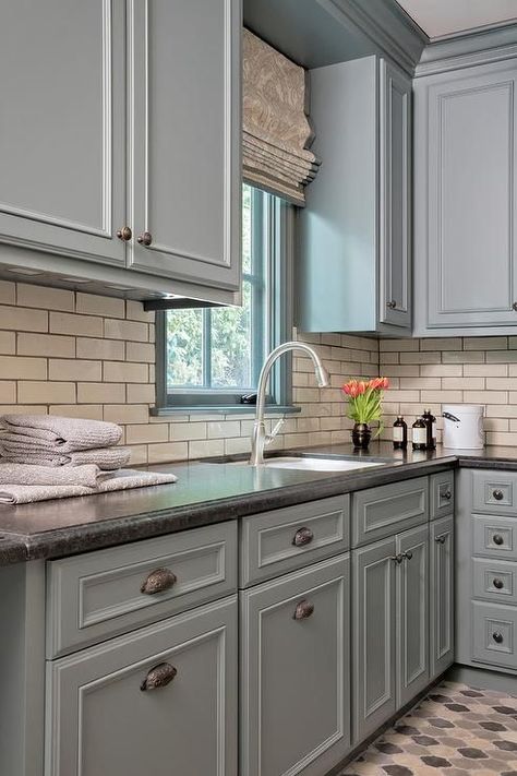 White and gray laundry room with honed black granite countertops featuring horizontal white backsplash tiles with gray grout. Gray Laundry Room Cabinets, Gray Laundry Room, Honed Black Granite, Black Kitchen Countertops, Grey Laundry Rooms, Outdoor Kitchen Countertops, Black Granite Countertops, Black Countertops, Gray Cabinets