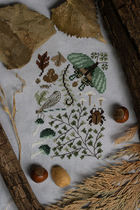 A mini cross stitch sampler in brown and green
earth tones with motifs of a swallowtail butterfly, a
damselfly with backstitched wings resting on some teal
mushrooms, a maidenhair fern, a rain beetle, fallen
leaves, and isopods. Cross Stitch Ideas, Random Crafts, Swallowtail Butterfly, Nature Walk, Needle Point, Stitch Art, Cross Stitch Rose, Stitching Art, Cross Stitch Art