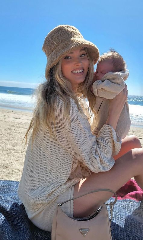 New mom Elsa Hosk was photographed on the beach wearing a Cream Organic Knit Sweater from Savannah Morrow ($247), Cream Organic Knit Ribbed Short from Savannah Morrow ($139), a Camel Teddy Bucket Hat from Lack Of Color ($79) and a Camo Beige Re-Edition 2000 Nylon Mini Bag from Prada ($795). To shop this look or buy this outfit on a budget, click the theninesfashion.com link. #ElsaHosk #SavannahMorrow #LackOfColor #Prada Mom Outfits Spring, Moms Goals, Foto Baby, Elsa Hosk, Future Mom, Mommy Life, Cute Family, Baby Family, Outfits With Hats