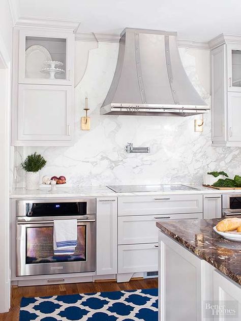 MUST SEE- MARBLE BACKSPLASH In the hands of skilled stone workers, marble can take on many forms. In this kitchen, the marble slab backsplash between the countertop and cabinets rises to artwork status behind the range. Crown molding emphasizes the marble, which echoes the shape of the range hood and handily highlights a pair of sconces that underscore this kitchen's fine furnishings./ Marble Slab Backsplash, Slab Backsplash, Kitchen Credenza, Marble Backsplash Kitchen, Marble Backsplash, Kitchen Hoods, Simple Kitchen, Kitchen Marble, Kitchen Trends