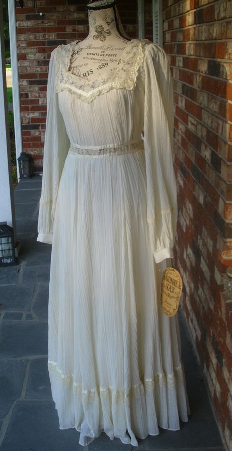 "This is a lovely, Romance Style Gunne Sax dress in a loosely woven, cream gauze, permanently pleated and running longitudinally with a dainty calico of violet flowers accenting the bodice and high waist (empire). There are gauze sashes on either side of the waist for adjustment.' The sleeves are unlined and billowing with a single button, calico cuff for whimsy. So much of it's beauty lies in its sumptuous skirting, simplicity and that 10 inch bottom ruffle living amongst ribbon and lace. Due t White Gunne Sax Dress, Gunne Sax Dress Vintage 70s, Light Cottagecore, Gunne Sax Wedding Dress, Antique Dress Form, Vintage Gunne Sax Dress, Coquette Princess, Pleaded Skirt, Stylish Kurtis Design