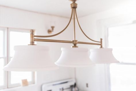 beautiful brass light fixture with three glass lamps in a victorian farmhouse Update Farmhouse, Chandelier Over Island, Victorian Farmhouse Kitchen, Victorian Light Fixtures, Farmhouse Kitchen Light Fixtures, Updated Victorian, Vintage Farmhouse Sink, Vintage Shelving, Farmhouse Kitchen Lighting