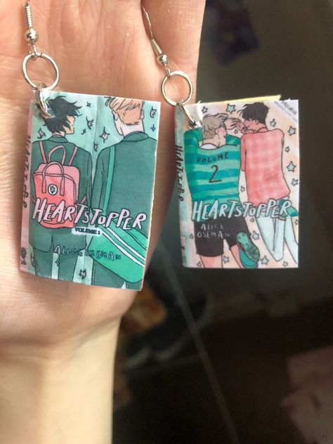 Heartstopper comic book earrings! Size: Length: 4cm Width: 2.5cm  Depth: 0.5m  Pictured next to my hand so you can get an idea of it's size  I love the heartstopper books and was inspired to make tiny little earrings out of them!  They're made by hand by me and as such aren't all exactly the same, so please excuse any small imperfections that come with handmade items ❤️ All Heartstopper Books, Heartstopper Earrings, Heartstopper Graphic Novel, Heartstopper Books, Bisexual Wallpaper Iphone Aesthetic, Reading Sheet Music, Bookshelf Art, Alice Book, Book Earrings