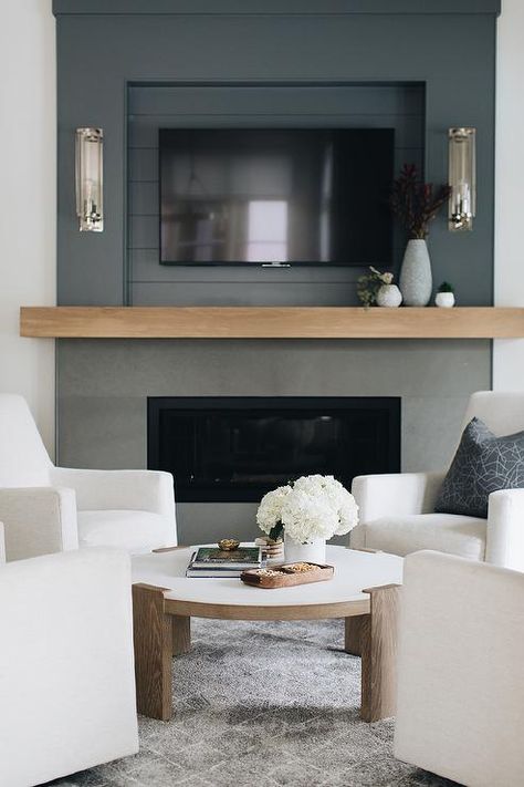 A flat-paneled television is mounted in a black shiplap niche surrounded by a black wall and fitted over a chunky tan wooden mantel paired with a black fireplace. Tv Niche, Shiplap Trim, Black Shiplap, Transitional Fireplace, Tv Over Fireplace, Wooden Mantle, Marble Fireplace Mantel, Linear Fireplace, Black Fireplace