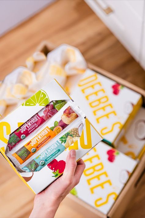 Hand holding box of DeeBee's SuperFruit organic freezer pops over a blurred background of DeeBee's packages on a kitchen floor. Tropical Snacks, Chocolate Drawing, Healthy Pantry, Creative Photography Projects, Brownie Ice Cream, Homemade Popsicles, Juicing For Health, Ice Pops, Organic Health