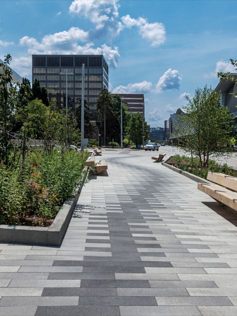 The final design suggests a boardwalk, using plank pavers through a riparian area which includes rain gardens and infiltration basins. The intent was to evoke movement through the space, while embracing the relationship to the Grand River which is only a block away, and providing areas of respite for downtown visitors and employees.
To achieve the desired paving pattern, three colors of 6” x 24” Promenade Plank Paver were used: Winter Marvel, French Grey and Midnight Sky in the Umbriano® finish. Paving Pattern Landscape, Diy Paving Ideas, Paver Block Design, Diy Paving, Pavers Walkway, Floor Pattern Design, Road Pavement, Paver Patterns, Pavement Design