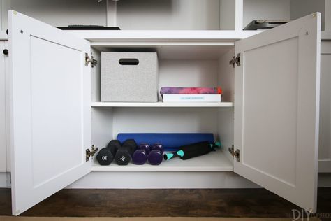 This Is How I Made My Living Room Into a Cheap, Secret Gym Hide Gym Equipment Living Rooms, Workout Gear Storage, Workout Equipment Storage, Gym Equipment Storage, Organized Ideas, Moving Advice, 12 Week Workout, Gym Organizer, Dumbbell Storage