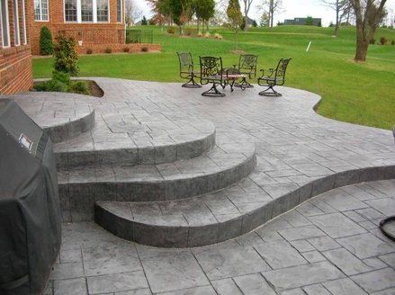 Add Interest to Your Patio A multi-level patio adds a bit of dramatic flair to a backyard stamped concrete design. Instead of a giant expanse of flat concrete, this homeowner chose a multiple level... Multi Level Stamped Concrete Patio, Multi Level Stone Patio, Concrete Patio With Step Down, Stamped Concrete Patio Ideas With Steps, Two Tier Concrete Patio, Multi Level Concrete Patio Ideas, Backyard Concrete Patio Ideas With Steps, Multi Level Patio Ideas, Tiered Concrete Patio