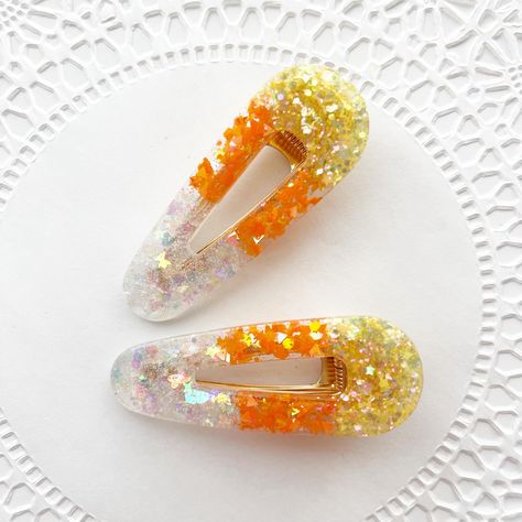 Add a sweet touch of Halloween spirit to your hair with these adorable sparkly Candy Corn Hair Clips! Perfectly capturing the iconic colors of candy corn, these clips feature a vibrant blend of yellow, orange, and white glitter in a smooth, glossy finish. The classic barrette shape makes them easy to wear and ideal for adding a playful, festive vibe to any hairstyle. Whether you're dressing up for Halloween or simply want to embrace the fall season, these clips are a fun and stylish way to do it Barrette Hairstyles, Candy Hair Clips, Halloween Claw Clips, Ghost Hair Clip, Halloween Resin Hair Clips, Halloween Hair Clips, Halloween Accessories Hair, Halloween Beads, White Candy